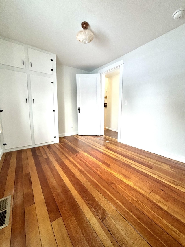 unfurnished bedroom featuring wood finished floors and visible vents