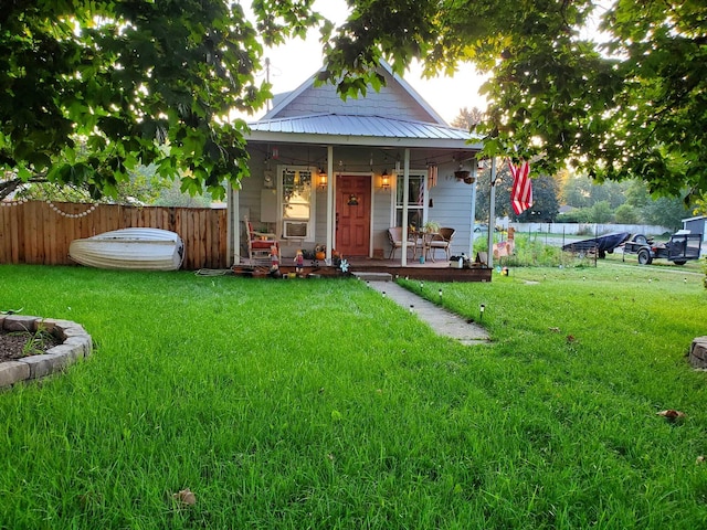 back of property featuring metal roof, fence, and a lawn