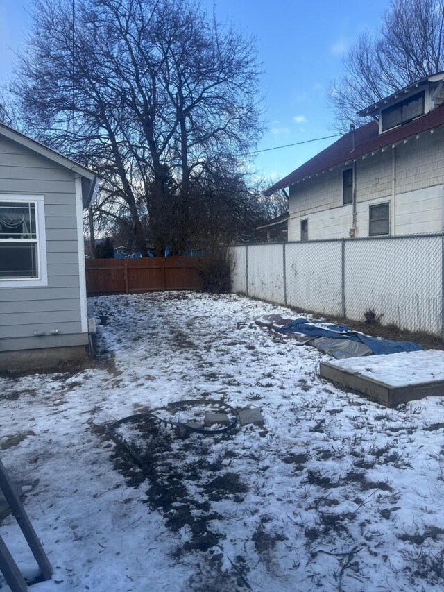 yard layered in snow with a fenced backyard