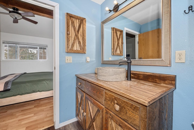 bathroom with baseboards, wood finished floors, vanity, and a ceiling fan