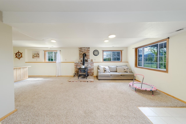 unfurnished living room with a wood stove, visible vents, baseboards, and carpet flooring