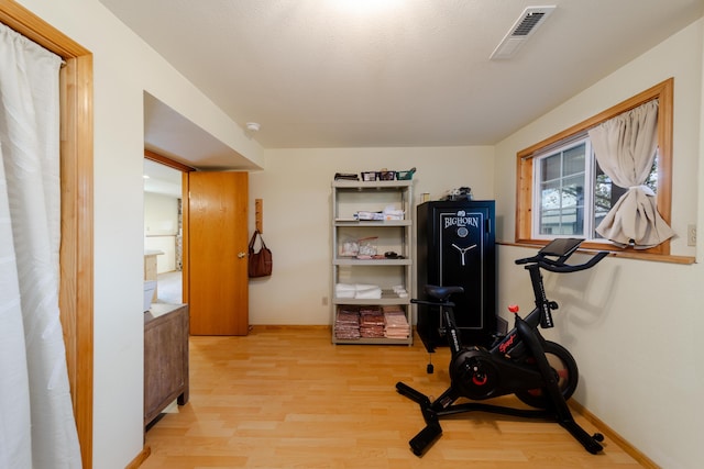 workout area featuring light wood finished floors, visible vents, and baseboards