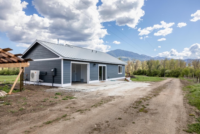 rear view of property featuring a garage, metal roof, ac unit, and a mountain view