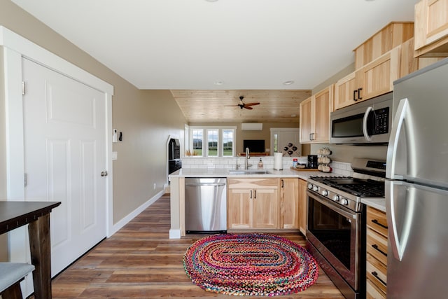 kitchen with a sink, stainless steel appliances, light countertops, and light brown cabinetry