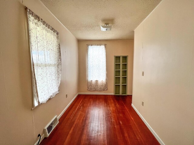 unfurnished room with dark wood-type flooring and a textured ceiling