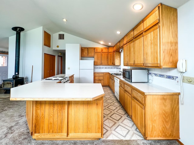 kitchen featuring a center island, white appliances, a wood stove, backsplash, and lofted ceiling