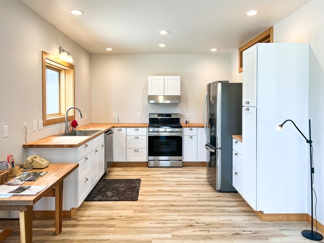 kitchen featuring appliances with stainless steel finishes, wood counters, white cabinetry, light hardwood / wood-style floors, and sink