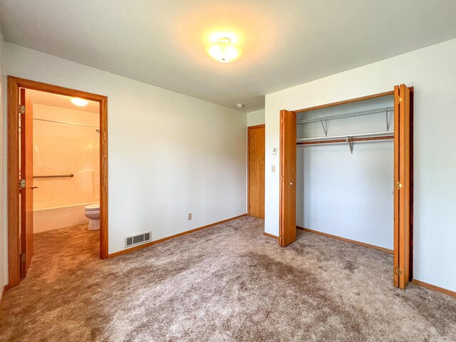 unfurnished bedroom with carpet floors, a closet, and ensuite bath