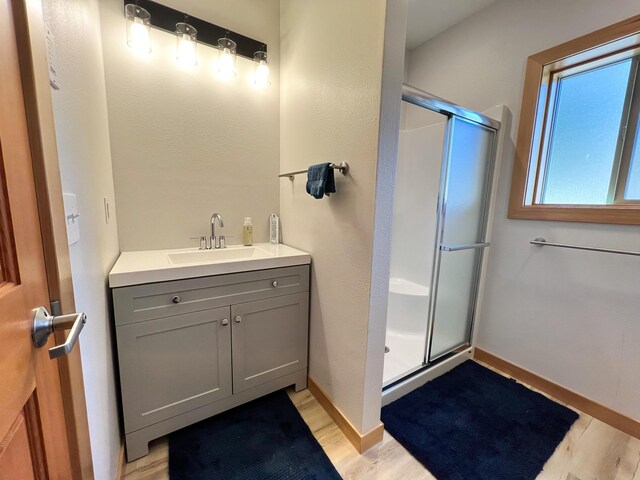 bathroom with vanity, a shower with shower door, and wood-type flooring