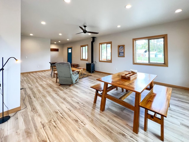 dining room with a wood stove, a wealth of natural light, and light wood-type flooring