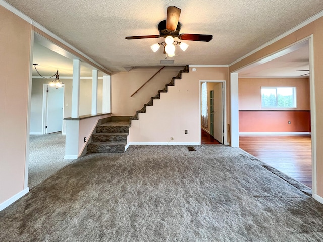 interior space featuring ceiling fan, dark carpet, ornamental molding, and a textured ceiling