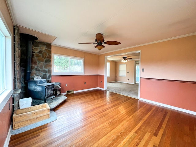 living room with hardwood / wood-style floors, a wood stove, and ornamental molding