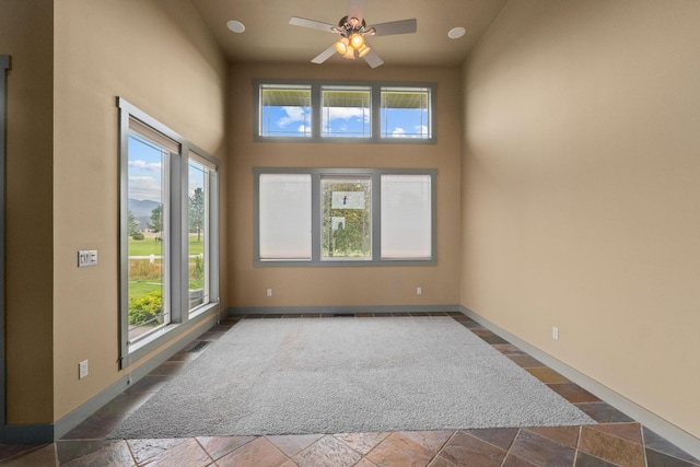 unfurnished room with a high ceiling and ceiling fan