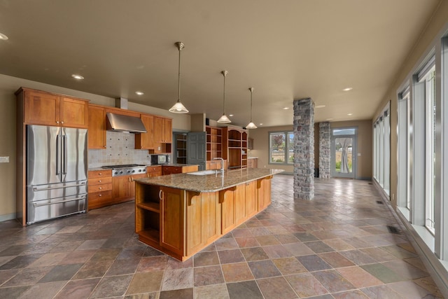 kitchen with stainless steel appliances, a kitchen breakfast bar, a spacious island, wall chimney exhaust hood, and ornate columns