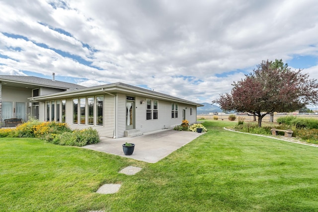 rear view of property featuring a lawn and a patio area