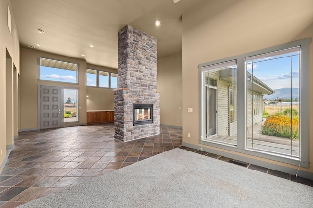 unfurnished living room with a high ceiling, a mountain view, a wealth of natural light, and a fireplace