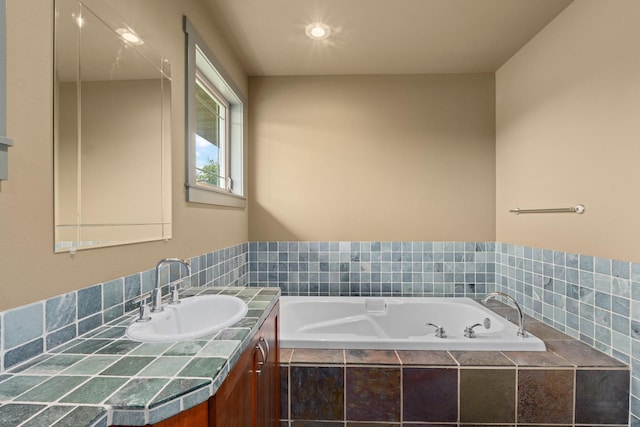 bathroom with tiled tub and vanity