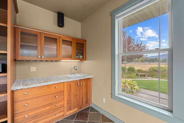 kitchen featuring dark tile patterned floors, sink, and tile countertops