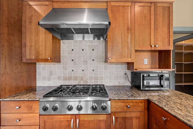 kitchen with extractor fan, decorative backsplash, stainless steel gas stovetop, and stone counters