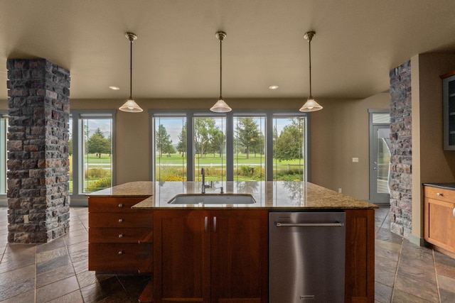 kitchen featuring light stone counters, a kitchen island with sink, sink, and hanging light fixtures