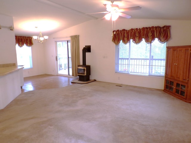 unfurnished living room featuring light carpet, ceiling fan with notable chandelier, vaulted ceiling, and a wood stove