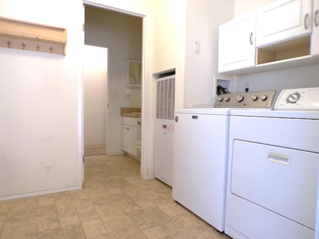 clothes washing area with cabinets and washer and dryer