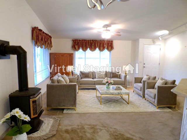 carpeted living room with ceiling fan, a wood stove, and track lighting