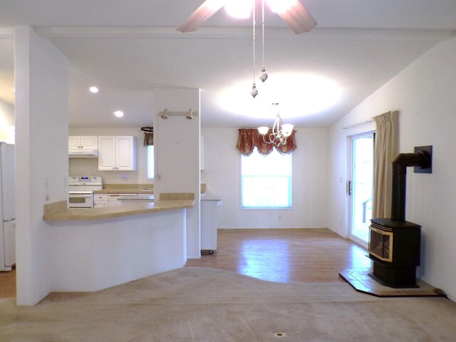 kitchen featuring white appliances, white cabinets, hanging light fixtures, kitchen peninsula, and vaulted ceiling