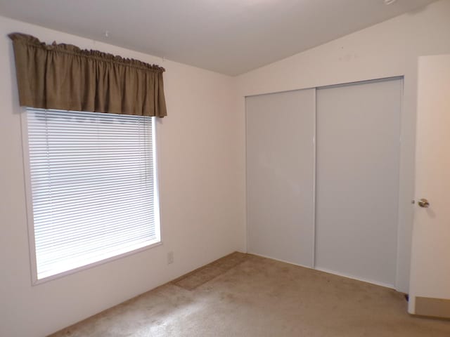 unfurnished bedroom with a closet, vaulted ceiling, and carpet floors