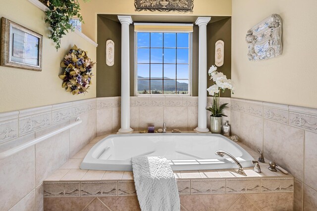 bathroom with decorative columns and tiled bath