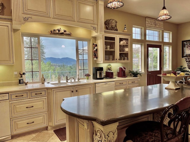 kitchen featuring pendant lighting, white dishwasher, sink, cream cabinets, and a mountain view