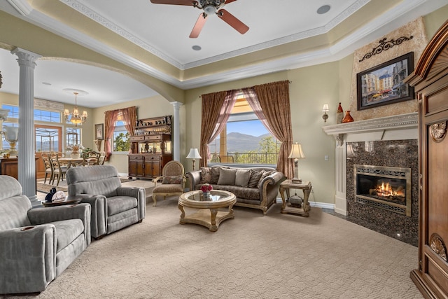 carpeted living room with a tray ceiling, ornamental molding, and ornate columns