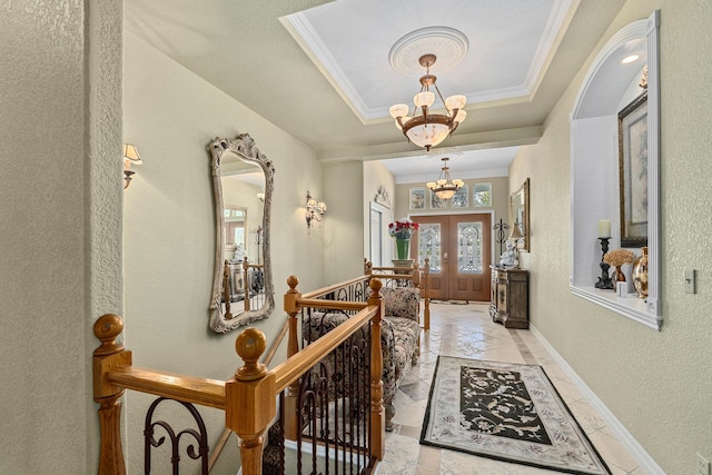 hallway featuring crown molding, french doors, an inviting chandelier, and a raised ceiling