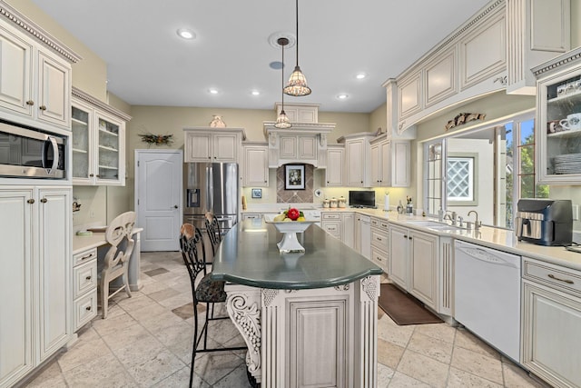 kitchen with a kitchen breakfast bar, pendant lighting, appliances with stainless steel finishes, sink, and a kitchen island