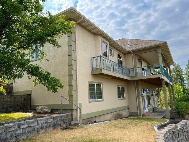 rear view of house with a balcony and a yard