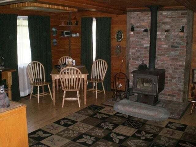 interior space with beam ceiling, a wood stove, wooden walls, and wood-type flooring