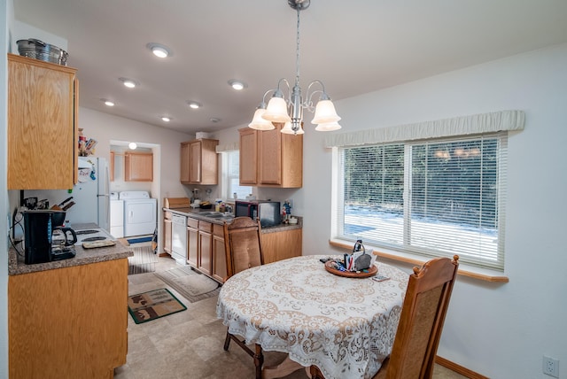 dining room featuring sink, vaulted ceiling, an inviting chandelier, and separate washer and dryer