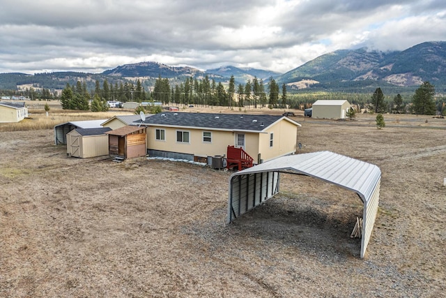 exterior space with central air condition unit, a mountain view, a carport, and a storage unit