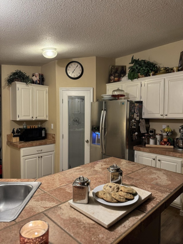 kitchen featuring white cabinets, tile counters, stainless steel fridge, and dark hardwood / wood-style flooring