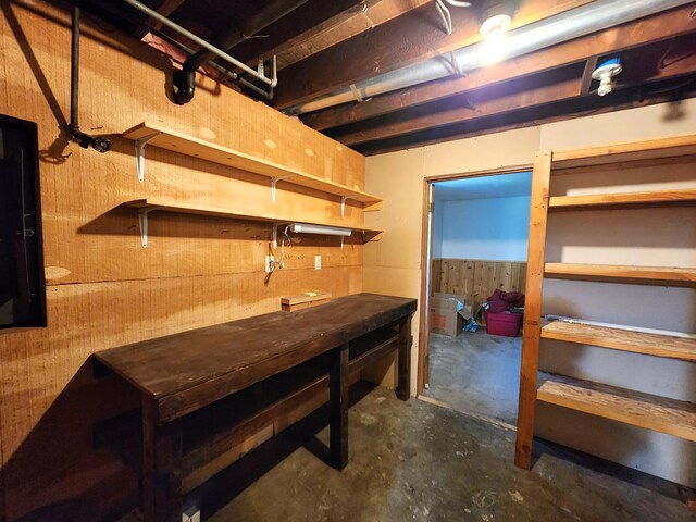 basement featuring wooden walls and a workshop area