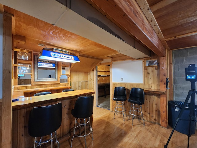 bar featuring light hardwood / wood-style floors, wood walls, and wooden counters