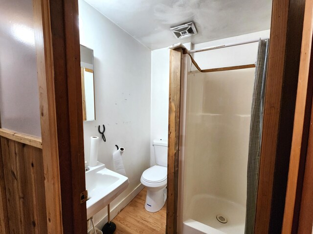 bathroom featuring sink, hardwood / wood-style flooring, toilet, and a shower