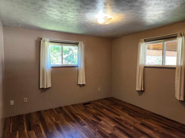 unfurnished room featuring dark hardwood / wood-style floors and a textured ceiling