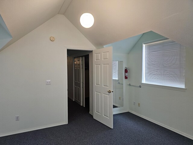 additional living space featuring dark carpet and lofted ceiling