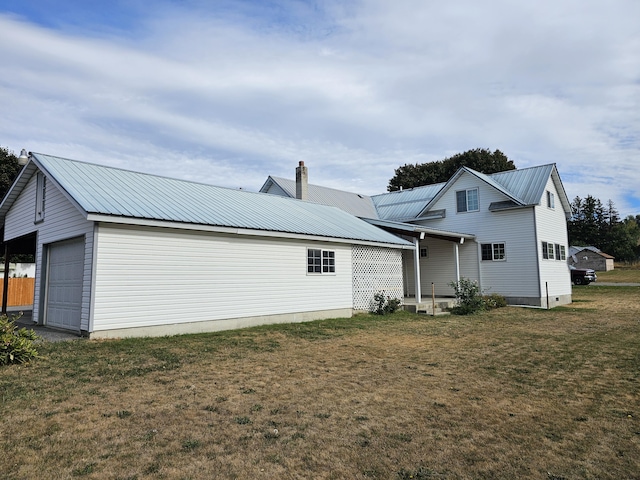 back of property featuring a garage and a lawn