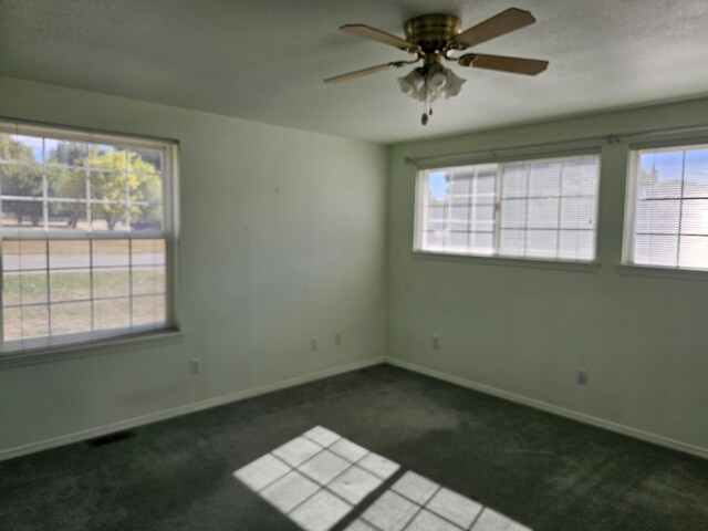 unfurnished room with ceiling fan and dark carpet