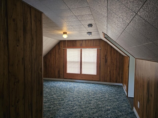 bonus room with wood walls, dark carpet, and lofted ceiling