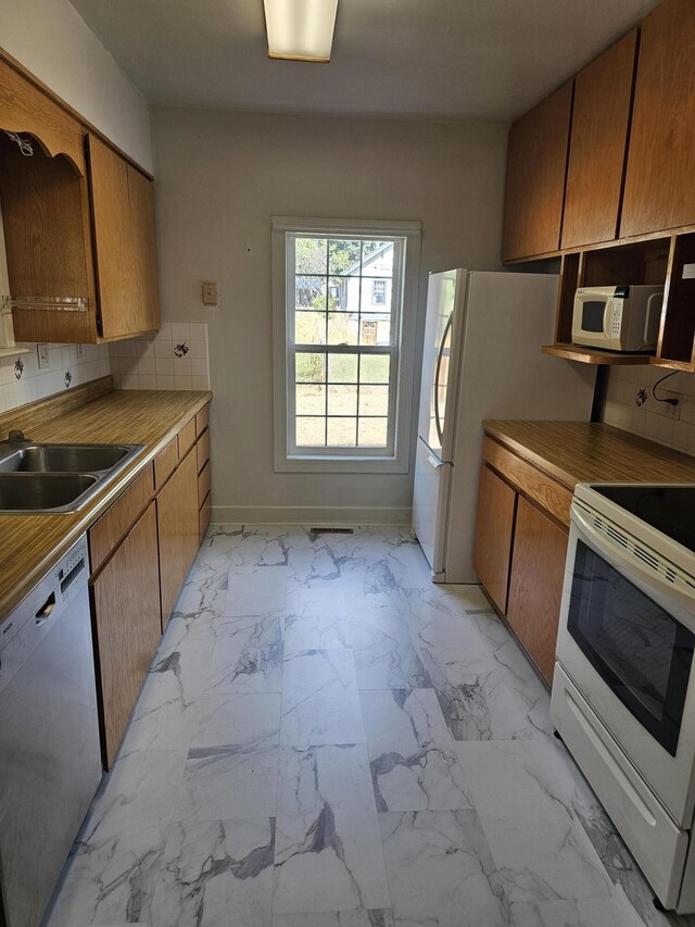 kitchen featuring sink, white appliances, and backsplash