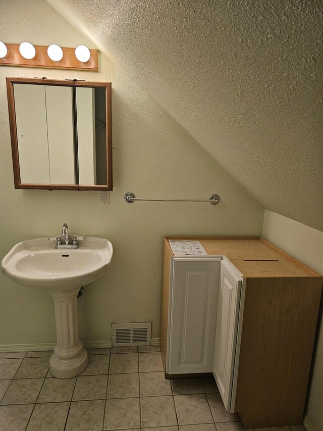 bathroom with a textured ceiling, tile patterned flooring, and vaulted ceiling