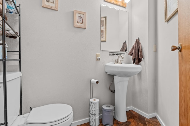 bathroom featuring toilet, a sink, and baseboards